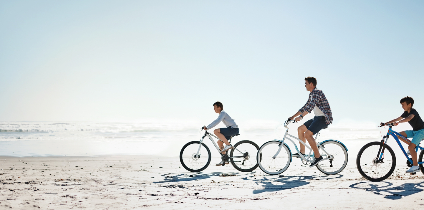 family riding bikes on beach