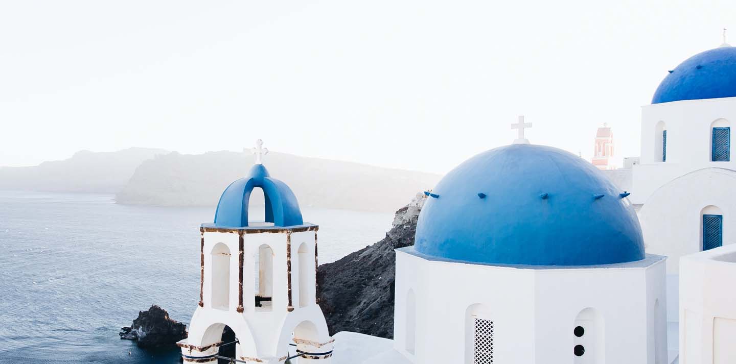 View of blue-domed buildings in Greece — travel insurance for international trips
