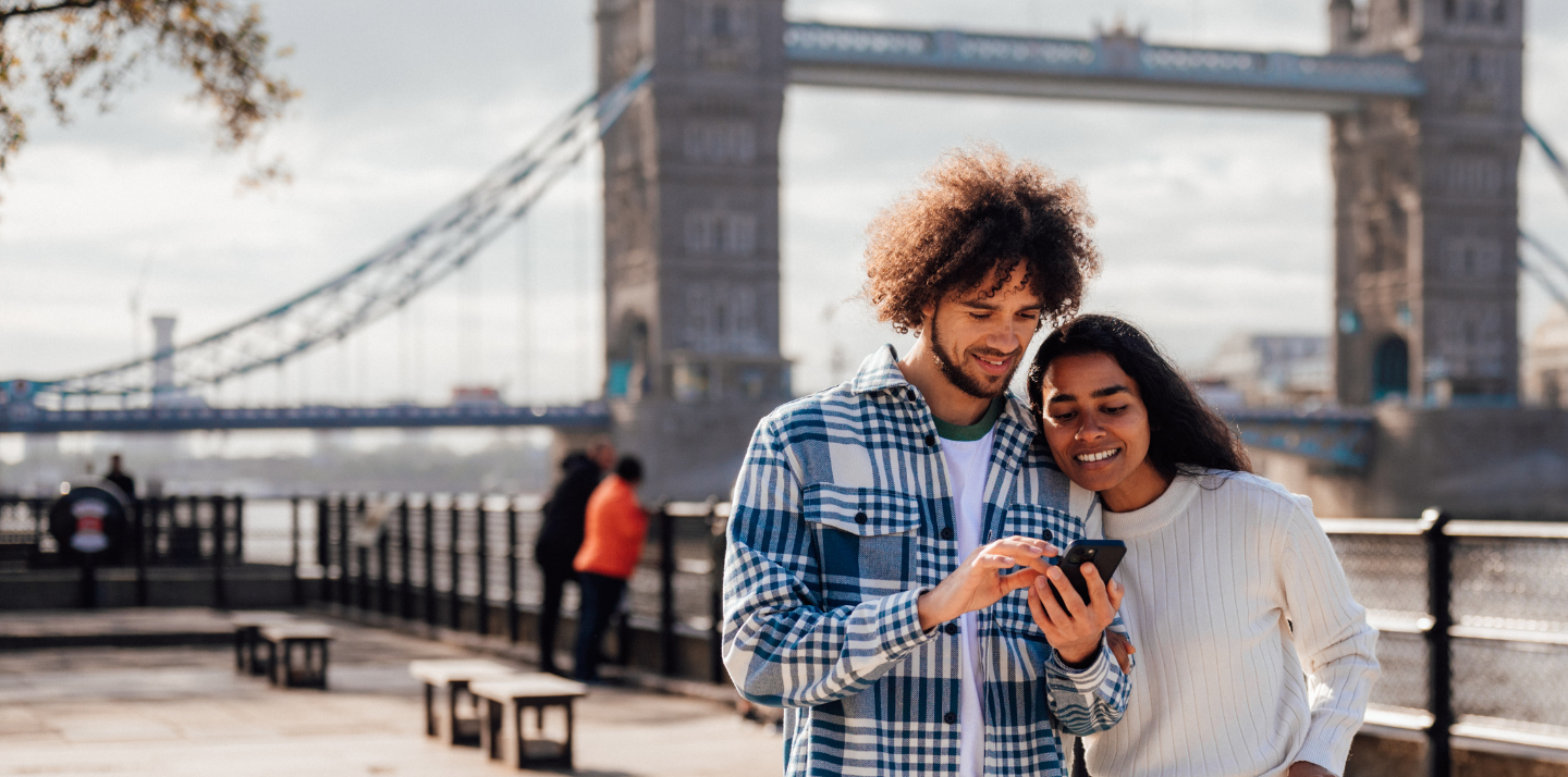 Couple in the U.K. smiling and looking at a travel app.