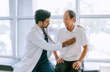 Doctor checking patient's heart at a travel health care appointment